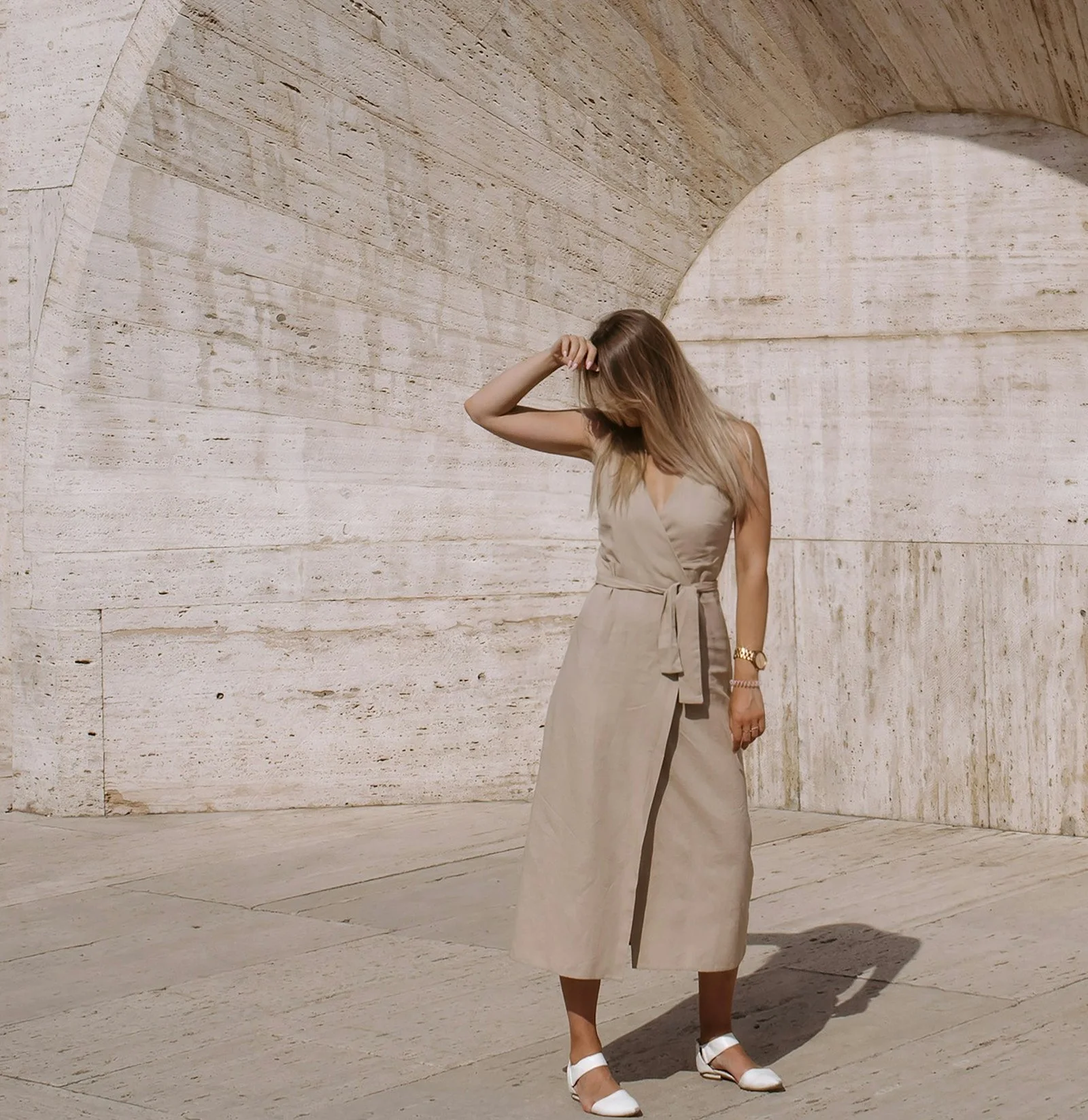 Woman in a bone Bonacieux dress standing under a stone arcade